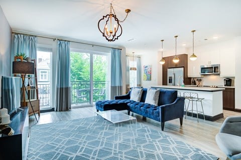 a living room with a blue couch and a kitchen with blue curtains